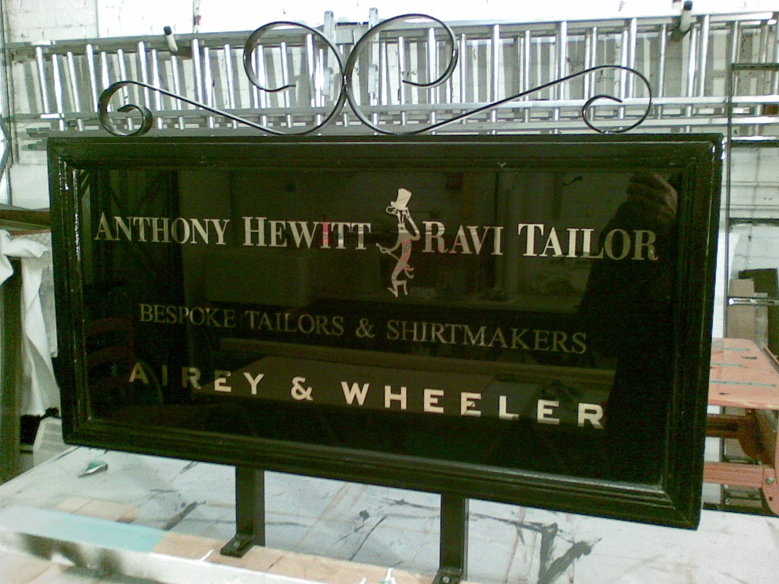Gilded glass sign in wooden frame with metal scrolls
