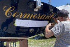 Painting the name on the stern of the Cormorant, sailboat. Toronto Island, 2021